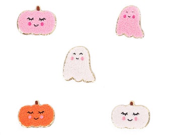 May include: Five felt Halloween patches, two pink pumpkins with smiling faces and two pink ghosts with smiling faces, and one orange pumpkin with a smiling face.