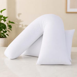 Könnte beinhalten: Ein weißes V-förmiges Kissen mit einem glatten, einfarbigen Stoffbezug. Das Kissen zeichnet sich durch ein markantes, abgewinkeltes Design aus, das sich zu einer stützenden Form wölbt und auf einer flachen Oberfläche liegt.
