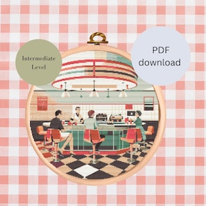 May include: Cross stitch pattern of a 1950s diner scene with four people sitting at the counter. The pattern is in a round hoop and has a checkered black and white floor. The pattern is labeled "Intermediate Level" and is available as a PDF download.