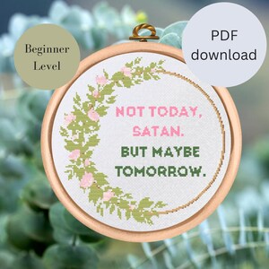 Könnte beinhalten: Ein weißer Kreuzstich-Stickrahmen mit einem grünen Blumenkranz und dem Text "NOT TODAY, SATAN. BUT MAYBE TOMORROW."