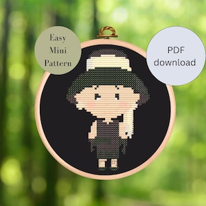 May include: A cross-stitch pattern of a cartoon character in a wooden embroidery hoop. The character has a hat, a dress, and long hair. The background is black. Text on the image says "Easy Mini Pattern" and "PDF download".