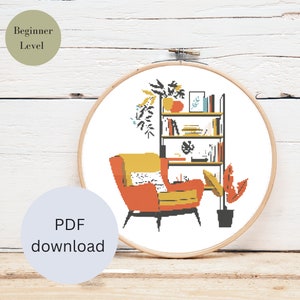 Könnte beinhalten: Kreuzstichmuster mit einer modernen Wohnzimmerszene aus der Mitte des Jahrhunderts mit einem orangefarbenen Sessel, einem Bücherregal und Topfpflanzen. Das Design ist in einem hölzernen Stickrahmen eingeschlossen. Der Text auf dem Bild lautet "Beginner Level" und "PDF download."