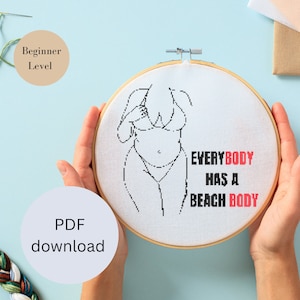 Könnte beinhalten: Ein weißer Stickrahmen mit einer schwarzen Linienzeichnung einer Person im Badeanzug. Der Text "EVERYBODY HAS A BEACH BODY" ist in schwarzen und roten Buchstaben geschrieben.