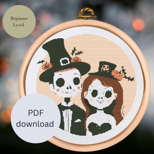 May include: A cross-stitch pattern featuring a couple dressed in Halloween costumes. The man is wearing a witch's hat and the woman is wearing a skull hat. Both have skeleton faces and are holding pumpkins. The pattern is labeled "Beginner Level" and "PDF download".