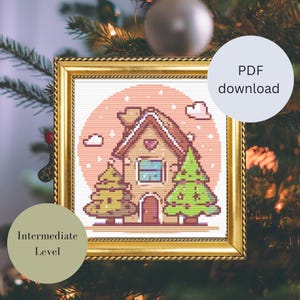 Könnte beinhalten: Kreuzstichmuster eines Lebkuchenhauses mit zwei grünen Weihnachtsbäumen, goldgerahmt. Der Hintergrund ist ein rosa Kreis mit weißen Wolken. Der Text auf dem Bild lautet "PDF download" und "Intermediate Level".