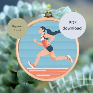 Könnte beinhalten: Ein Kreuzstichmuster einer Frau, die auf einer Laufbahn läuft. Das Muster ist für Anfänger geeignet und als PDF-Download verfügbar.