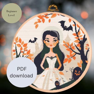 May include: A cross-stitch pattern featuring a cartoon woman in a white dress with black accents, standing in a forest with orange and brown leaves. Bats fly overhead and a jack-o-lantern is visible in the background. The pattern is labeled "Beginner Level" and "PDF download".