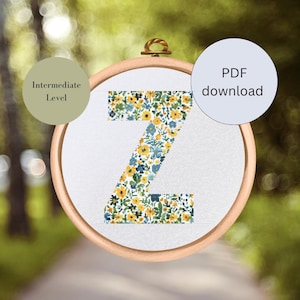 Könnte beinhalten: Ein Kreuzstichmuster des Buchstabens Z, gefüllt mit gelben und blauen Blumen. Das Muster ist in einem Holzreifen gerahmt und als Projekt für Fortgeschrittene gekennzeichnet. Der Text "PDF-Download" ist in der oberen rechten Ecke des Bildes sichtbar.