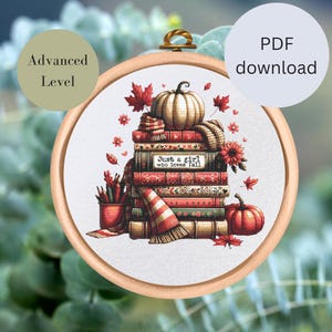 Könnte beinhalten: Kreuzstich-Design in einem Holzrahmen mit einem Bücherstapel, einem Kürbis und Herbstblättern. Der Text "Just a girl who loves fall" ist auf einem Buch zu sehen. Enthält einen Stifthalter und einen Schal. Das Design ist mit "Advanced Level" und "PDF-Download" gekennzeichnet.