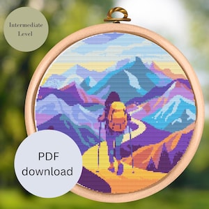 Könnte beinhalten: Ein Kreuzstichmuster, das einen Wanderer mit Rucksack zeigt, der auf einem Pfad durch eine farbenfrohe Berglandschaft geht. Das Muster ist in einem Holzrahmen eingefasst und mit "PDF-Download" und "Mittleres Niveau" beschriftet.