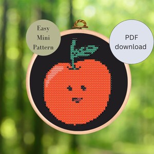 Könnte beinhalten: Ein Kreuzstichmuster einer roten Apfel mit einem lächelnden Gesicht in einem hölzernen Stickrahmen. Das Muster ist mit "Easy Mini Pattern" beschriftet und als PDF-Download verfügbar.