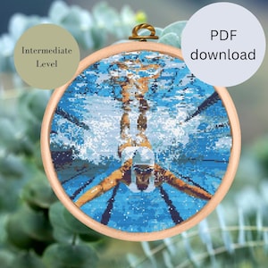 Puede incluir: Patrón de punto de cruz de un nadador en una piscina. El patrón está en un aro redondo y es de nivel intermedio.