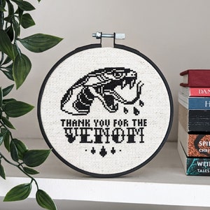 May include: Black and white embroidery hoop with a snake and the text "Thank you for the venom".