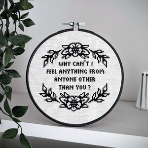 Puede incluir: Aro de bordado blanco y negro con el texto "Why can't I feel anything from anyone other than you?" rodeado de diseños florales.