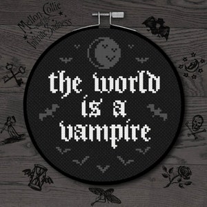 Może przedstawiać: Czarno-biały tamborek do haftu z tekstem "the world is a vampire" w stylu gotyckim. Tamborek jest otoczony przez nietoperze, gwiazdy i półksiężyc.