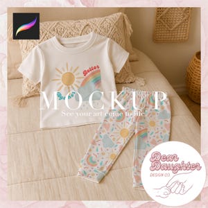 Peut inclure: Un t-shirt blanc avec un motif arc-en-ciel, soleil et nuages. Le texte "Better" est sur l'arc-en-ciel. Le t-shirt est associé à un pantalon blanc avec un motif arc-en-ciel, soleil et nuage. Le texte "Dear Daughter Design Co." est sur un cercle blanc avec un contour rose.