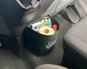 May include: A black felt organizer with a white mountain and trees design hangs in a car. The organizer is filled with items like a roll of paper towels, a can of soda, and a bottle of liquid.