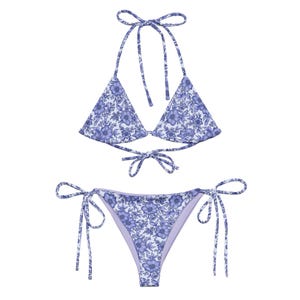 May include: A two-piece bikini set with a floral pattern in shades of blue and white. The top is a halter style with triangle cups, and the bottoms are a classic cut with tie sides. The swimwear is designed for a comfortable and stylish fit.