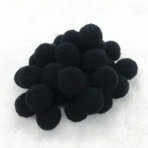 May include: A pile of black pom poms. The pom poms are soft and fluffy and would be great for crafts or decorations.