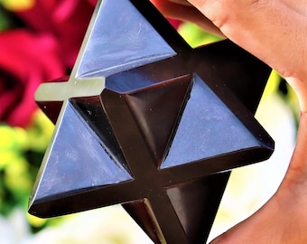 May include: A black obsidian Merkabah, a geometric shape representing spiritual energy, with a star-like design. The Merkabah is a popular crystal for meditation and spiritual practices.