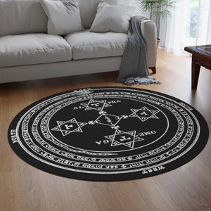 May include: Black and white round rug with a circular design featuring a star of David, the words "Alpha" and "Omega", and other symbols. The rug is on a wooden floor in a living room setting.