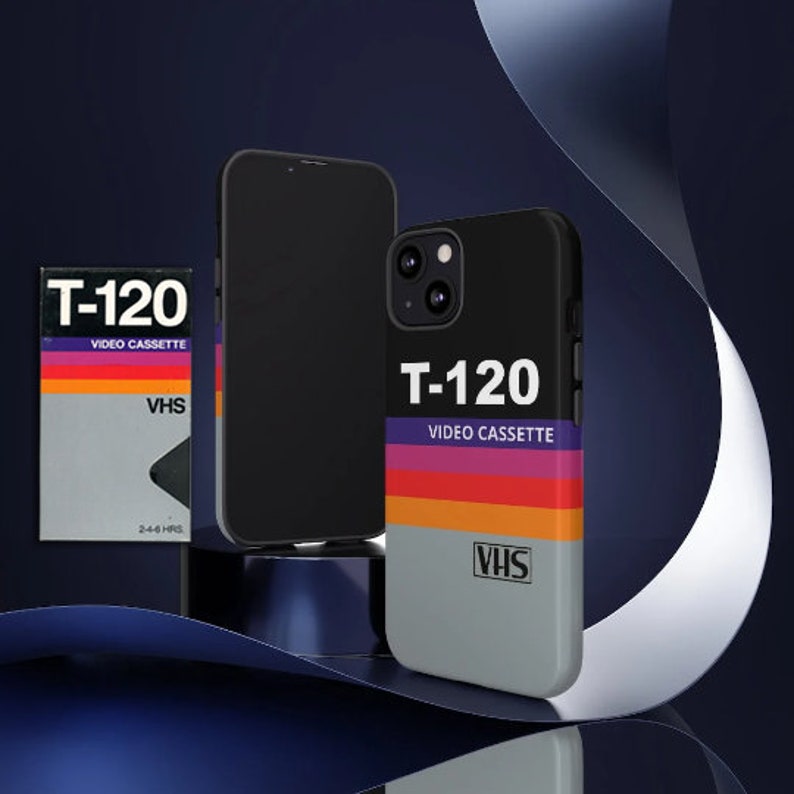 Może przedstawiać: Czarne i szare etui na telefon z retro wzorem kasety VHS. Etui zawiera napis "T-120 VIDEO CASSETTE" i "VHS" białymi literami.
