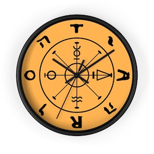 May include: A round wall clock with a black frame and a light orange face. The clock features black hands and a central circular design with various black symbols and characters arranged around the perimeter, including the letters T, A, R, and O.