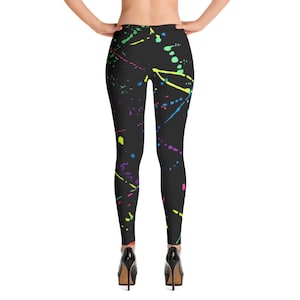 May include: Black leggings with a colorful paint splatter design. The leggings have a high waist and a fitted silhouette.