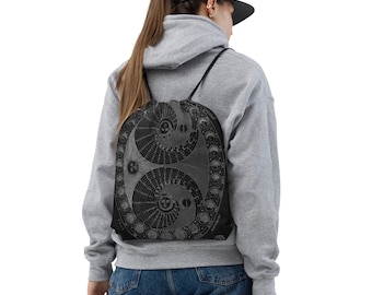May include: A black drawstring bag with a white and gray design of a celestial map with moons and stars. The bag is being worn by a person.