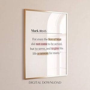 May include: A framed wall art print featuring the Bible verse Mark 10:45 in black serif text on a white background. Specific phrases are highlighted with soft tan and pink brushstroke accents. The frame is a thin, metallic gold color.