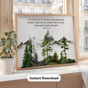 May include: A framed wall art print featuring a watercolor-style mountain landscape with evergreen trees and rocks. The text reads: I LIFT UP MY EYES TO THE HILLS, FROM WHERE WILL MY HELP COME? MY HELP COMES FROM THE LORD, WHO MADE HEAVEN AND EARTH PSALM 121:1-2.