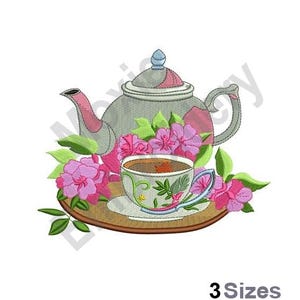May include: A gray teapot with pink accents and a floral design sits on a tray with a teacup and saucer. Pink flowers surround the teapot and teacup.