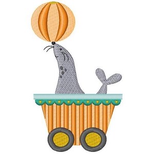 May include: A gray seal balancing an orange ball on its nose while sitting in a striped wagon with teal trim and yellow wheels.