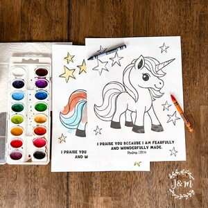 Op de afbeelding: Een kleurplaat met een zwart-witte illustratie van een eenhoorn met een regenboogstaart en -manen. De pagina bevat de tekst "Ik prijs u, want ik ben wonderbaarlijk gemaakt. Psalm 139:14". De pagina is omringd door sterren en wordt vergezeld door een set aquarelverf en kleurpotloden.