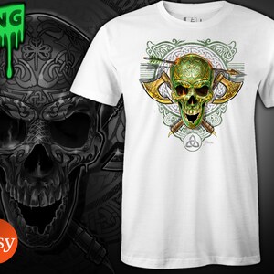 May include: White t-shirt with a green skull design. The skull is surrounded by Celtic knotwork and two crossed axes. The skull has a green and gold design and is pierced by an arrow.