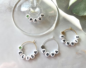 May include: Four gold and silver wine glass charms with white beads that spell out the names "Paul", "Yanni", "Anna", and "Lisa". Each charm has a small green shamrock.