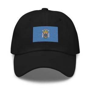 Könnte beinhalten: Eine schwarze Baseballkappe mit einer blauen und weißen Flagge mit einem Wappen auf der Vorderseite.