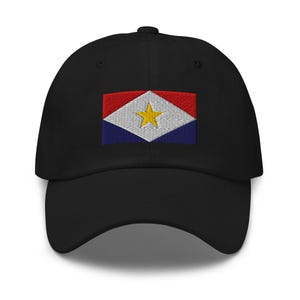 Peut inclure: Une casquette de baseball noire avec un drapeau brodé de Sint Maarten. Le drapeau est rouge, blanc, bleu et jaune avec une étoile à cinq branches.