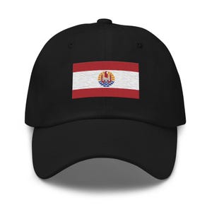 Peut inclure: Une casquette de baseball noire avec un drapeau de la Polynésie française brodé. Le drapeau est rouge, blanc et bleu avec un soleil et une roue de navire stylisée.