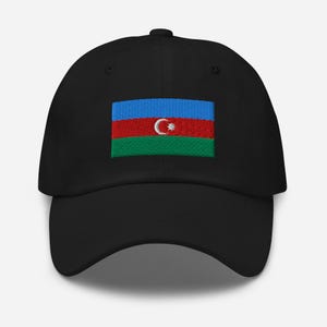 Può includere: Un cappello da baseball nero con una bandiera dell'Azerbaigian ricamata. La bandiera è blu, rossa e verde con una mezzaluna bianca e una stella.