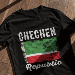 May include: Black t-shirt with a white distressed graphic of the Chechen Republic flag and the text "Chechen Republic".