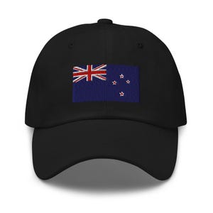 May include: A black baseball cap featuring an embroidered New Zealand flag. The flag is blue with a red and white Union Jack in the top left corner and four red stars in the bottom right corner.