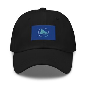 May include: A black baseball cap with a blue and white flag featuring a stylized sail and a circle of stars. The flag is centered on the front of the cap.