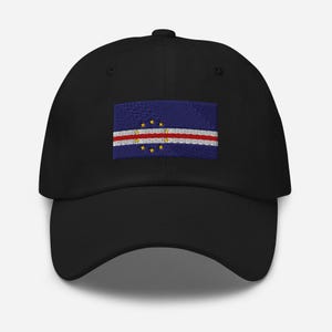 Peut inclure: Une casquette de baseball noire avec un drapeau du Cap-Vert brodé. Le drapeau est bleu avec une bande blanche et des étoiles jaunes.