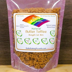 May include: A clear plastic bag filled with rough-cut natural butter toffee bits. The bag has a label with the brand name "Bella Accents" and details about the product, including "Gluten Free" and "Natural Flavor". The net weight is 8 oz (227g).