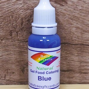 May include: A blue gel food coloring bottle with a white cap. The label reads "Bella Accents Natural Gel Food Coloring Blue." The bottle is against a wood grain background. The product is pet safe and dye free.