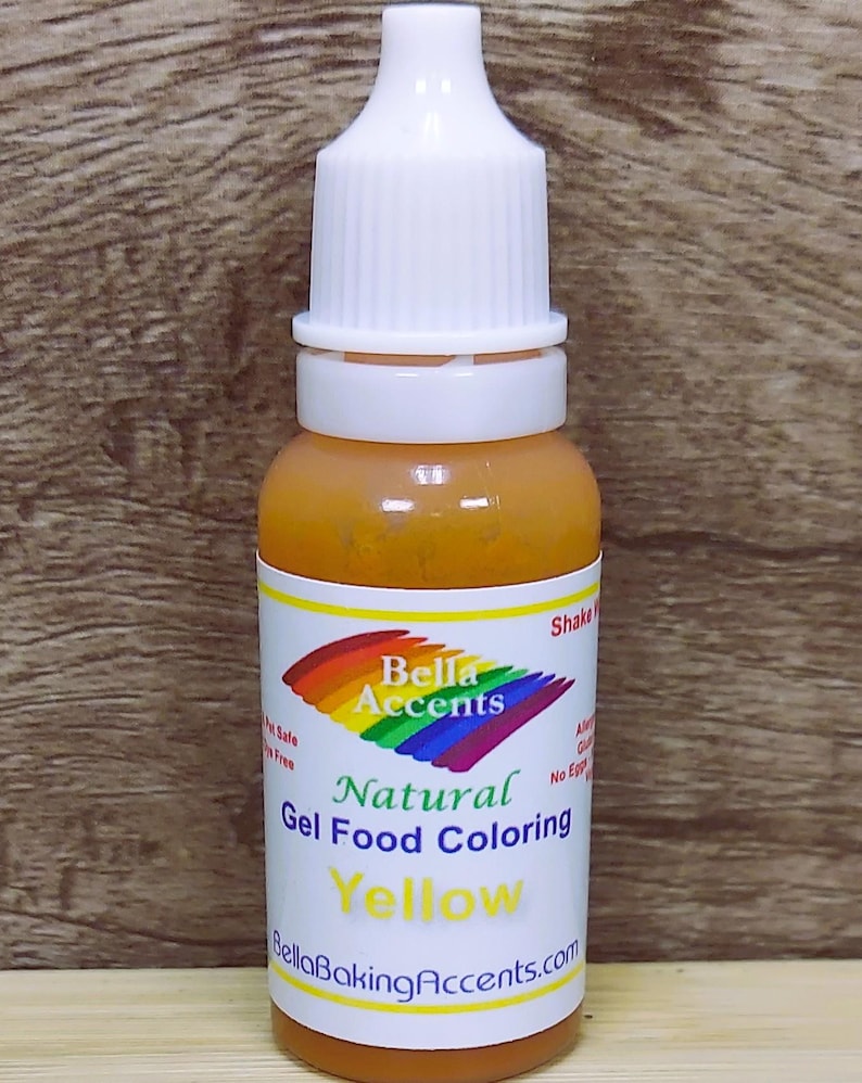 May include: A bottle of yellow natural gel food coloring. The label features the brand name "Bella Accents" with a rainbow design. The bottle has a white cap and is filled with a yellow liquid. The text "Yellow" is prominently displayed on the label.
