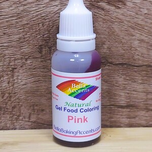 May include: A bottle of pink natural gel food coloring. The label features the text "Bella Accents" above "Natural Gel Food Coloring Pink" and "BellaBakingAccents.com". The bottle has a white cap and a clear body.