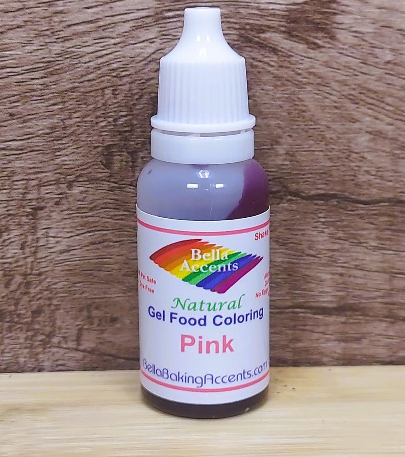 May include: A bottle of pink natural gel food coloring. The label features the text "Bella Accents" above "Natural Gel Food Coloring Pink" and "BellaBakingAccents.com". The bottle has a white cap and a clear body.