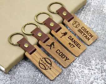May include: Four wooden keychains with leather straps and metal rings. Each keychain features a baseball-themed design with a player silhouette and text, including "Coach Bryan", "Daniel #17", "Cody", and "Jackson".